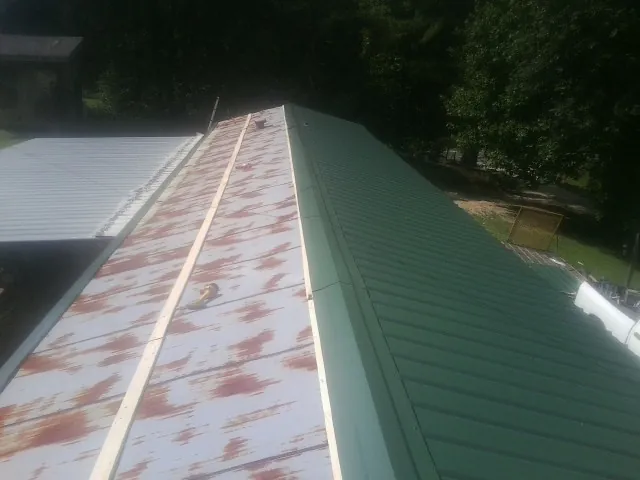 Old rusted panels beside newly installed green metal roofing — Wind Damage Roof Repair by Roofing Brothers in Saukville