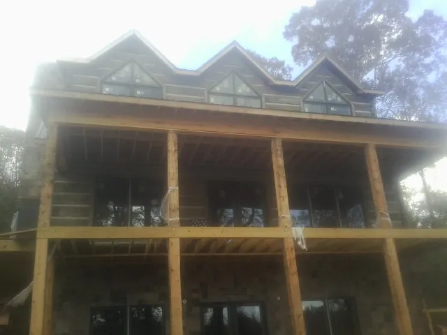 Dormers and porch framing on a large log home under construction — Roof Coating work by our crew in Saukville