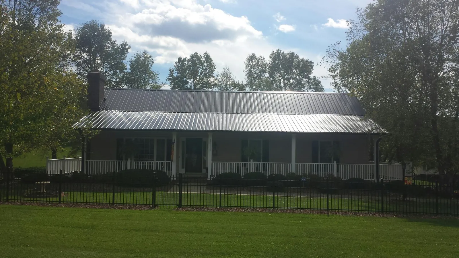 Gray metal roof on a brick ranch with a full width front porch — Gutter Guard Installation work by our crew in Saukville