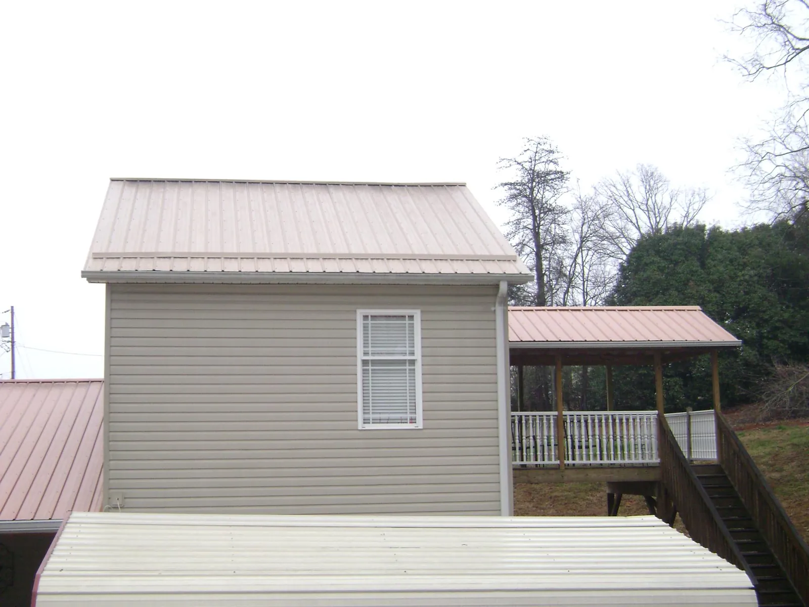 Tan metal roofs on a two story addition and attached porch, from a Roof Replacement job in Saukville