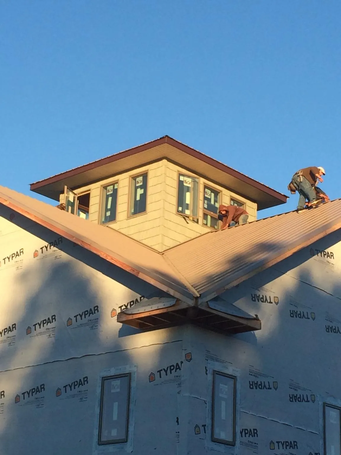 Roofers working around a rooftop cupola on a new metal roof at sunset — Roof Waterproofing in Saukville by Roofing Brothers